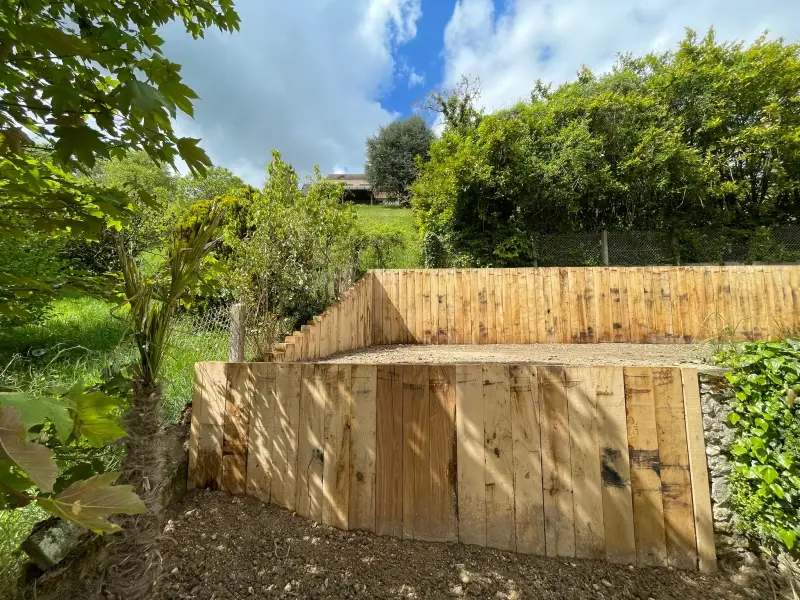 Mur de soutènement en bois et terrasse de jardin aménagée dans le Vexin